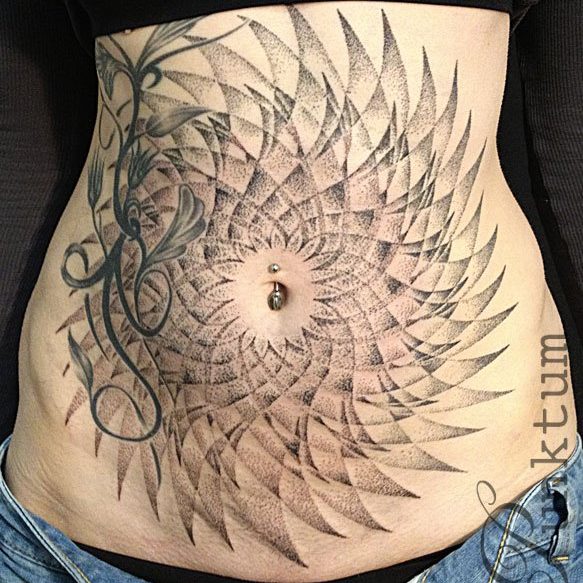 A spiral tattoo radiating out from a pierced belly button, intersecting a floral tattoo on someone's torso.
